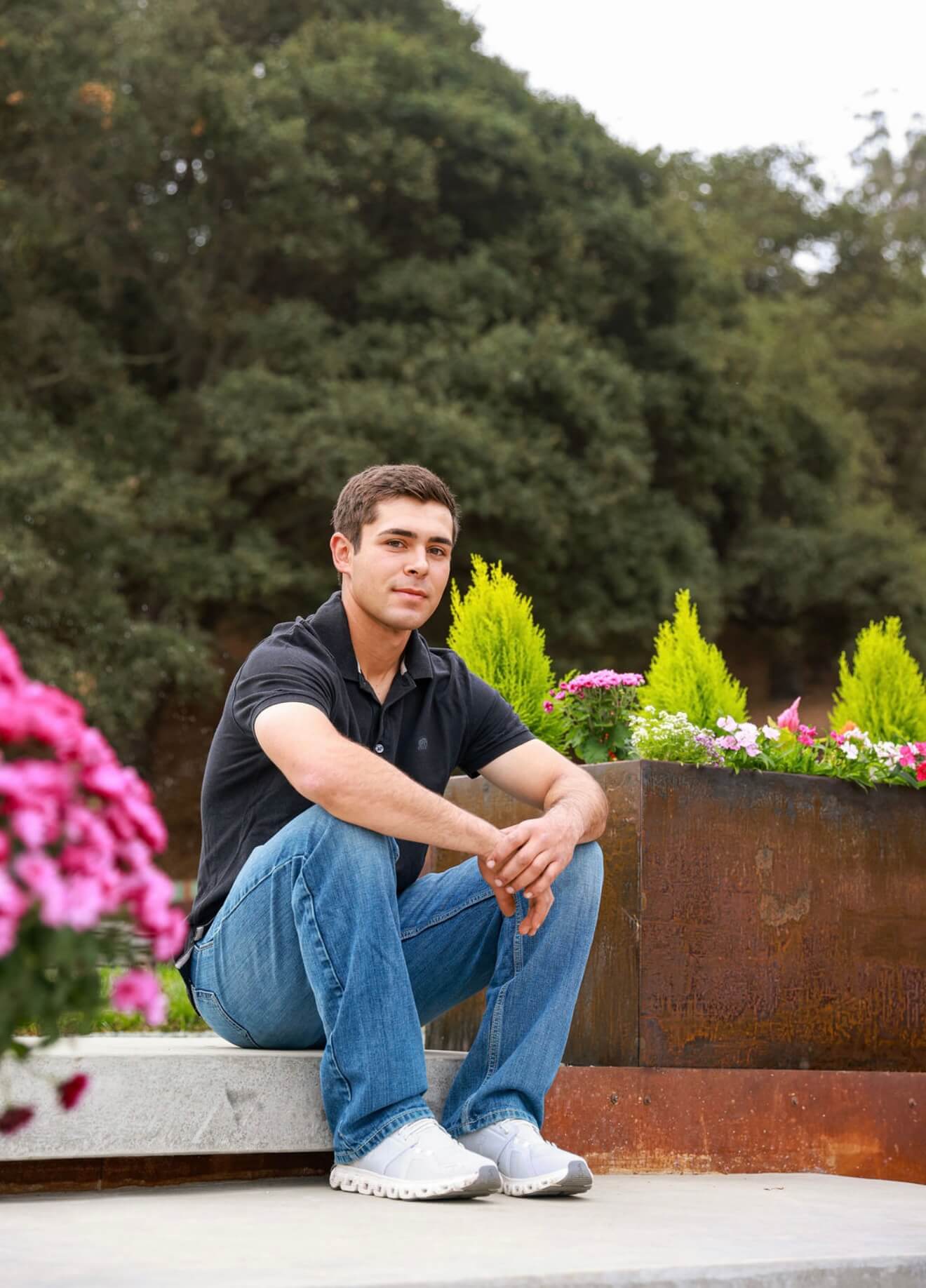 Portrait of Moises Hernandez sitting beside handcrafted Corten steel planters in a landscaped outdoor setting.